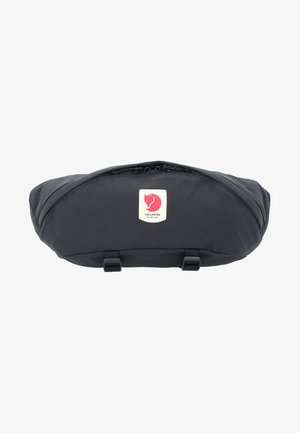 Sacoche noire à taille avec une forme courbée, fabriquée en tissu durable. Dotée d'une fermeture éclair, de bretelles ajustables et d'un détail de logo distinct en blanc et rouge.