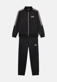 Survêtement noir comprenant une veste zippée avec des rayures blanches sur les épaules et un pantalon assorti avec une taille élastique et un détail de logo.