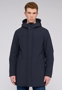 Námořnická modrá voděodolná parka s kapucí, předním zipem, patentkami, dvěma bočními kapsami, hladkou texturou a rovnými liniemi.