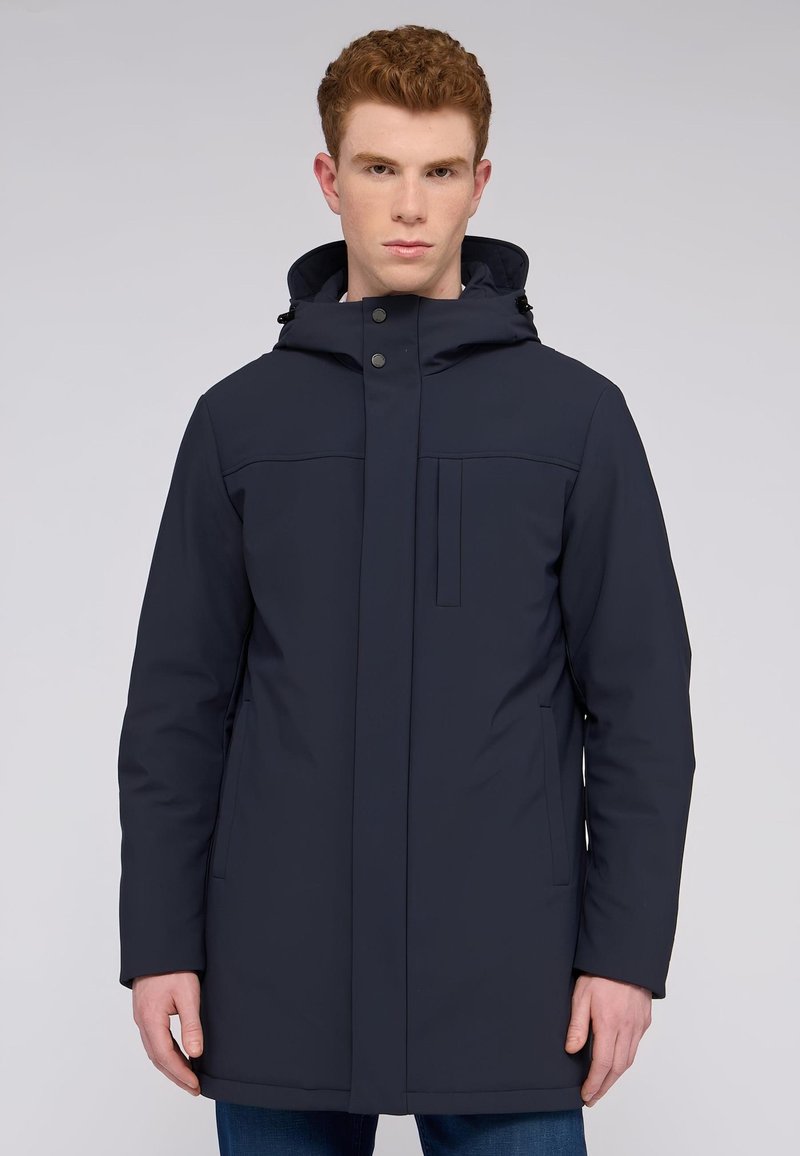 Námořnická modrá voděodolná parka s kapucí, předním zipem, patentkami, dvěma bočními kapsami, hladkou texturou a rovnými liniemi.