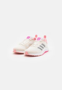 Beige athletic shoes with a mesh upper, pink accents, gray stripes, and a textured sole. Features padded collar and contrasting outsole.