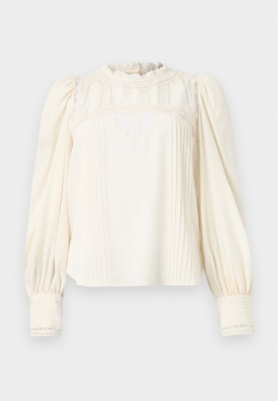 Kremowa bluzka z wysokim, falbaniastym dekoltem, misternym koronkowym wykończeniem, plisowanym przodem i bufiastymi rękawami. Manżety mają pionowe paski i koronkowe wykończenie.