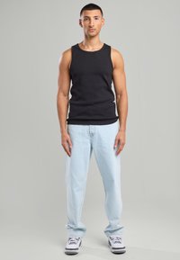 Mustapaita, vaaleansiniset farkut, harmaa-valkoiset lenkkarit. Yksinkertainen muotoilu, rento istuvuus. Silkkinen kangas ja epämuodollinen tyyli.