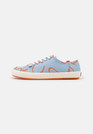 Lichtblauwe canvas sneaker met oranje abstracte patronen, witte veters en een witte zool met een oranje onderkant, gezien van de zijkant.
