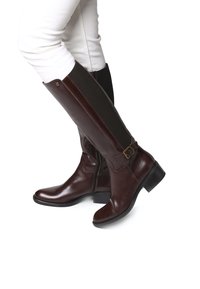 Bottes en cuir marron montantes avec une fermeture éclair latérale, un accent de boucle et un panneau en tissu texturé. Design à talon plat, forme élégante.