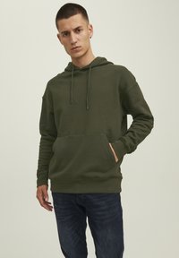 Olivgrüner Hoodie mit einer Kängurutasche, Kapuze mit Zugband, gerippten Bündchen und Saum, kombiniert mit dunkelblauen Jeans. Weicher, strukturierter Stoff.