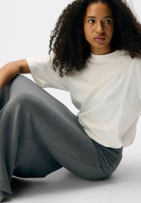 White short-sleeve tee paired with a long, flowing, gray skirt. The fabric appears soft with a smooth texture. The outfit is casual and comfortable.