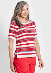 Gebreid T-shirt met korte mouwen, voorzien van horizontale rood, wit en blauwe strepen, textuurpatronen en een gebogen zoom. Gestyled met rode broeken.