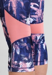 Compression leggings featuring a navy base with vibrant pink palm leaf patterns and textured coral panels on the sides.