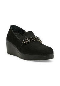 Scarpe con zeppa in suede nero caratterizzate da una superficie liscia, un elastico frontale e decorazioni a catena sul collo del piede.