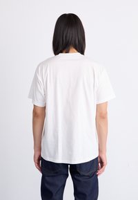 Korte mouwen witte katoenen t-shirt met een ronde hals, met een losse pasvorm en een zachte textuur. Draagt bij donkere denim jeans.