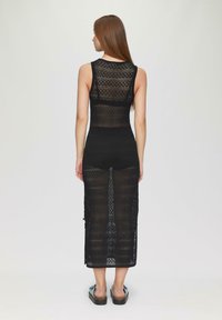 Schwarzes ärmelloses Kleid mit einem strukturierten Strickmuster, knöchellang, mit eng anliegender Passform und Seitenschlitzen für Bewegungsfreiheit.
