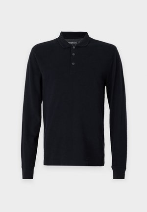Svart langermet polo skjorte med krage, tre-knaps placket og ribbede mansjetter. Laget av et mykt, teksturert stoff.