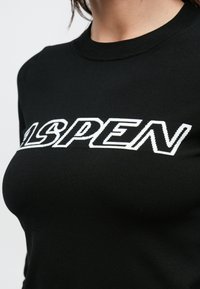 Schwarzer Strickpullover mit weißer "ASPEN"-Beschriftung. Rundhalsausschnitt und strukturierter Stoff mit einer körpernahen Passform.