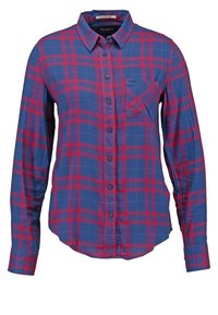 Chemise à manches longues à carreaux bleus et rouges, avec col et poche poitrine côté gauche.