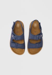 Σανδάλια σκούρου μπλε με δύο ρυθμιζόμενους ιμάντες βέλκρο, επενδυμένο πέλμα και καφέ λαστιχένια σό λα. Μαλακό υφασμάτινο πάνω μέρος με στρογγυλή μύτη.