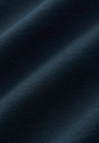Sötét tengerészkék szövet, finom bordázott textúrával, sima, puha anyag hullámait mutatva be, amely egyenletes és homogén felületi mintázattal rendelkezik.
