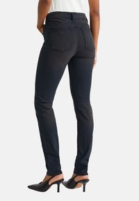 Vysoké čierne džínsy, slim-fit strih, s dvoma zadnými vreckami a hladkou textúrou. Skombinované s čiernymi slingback podpätkami.