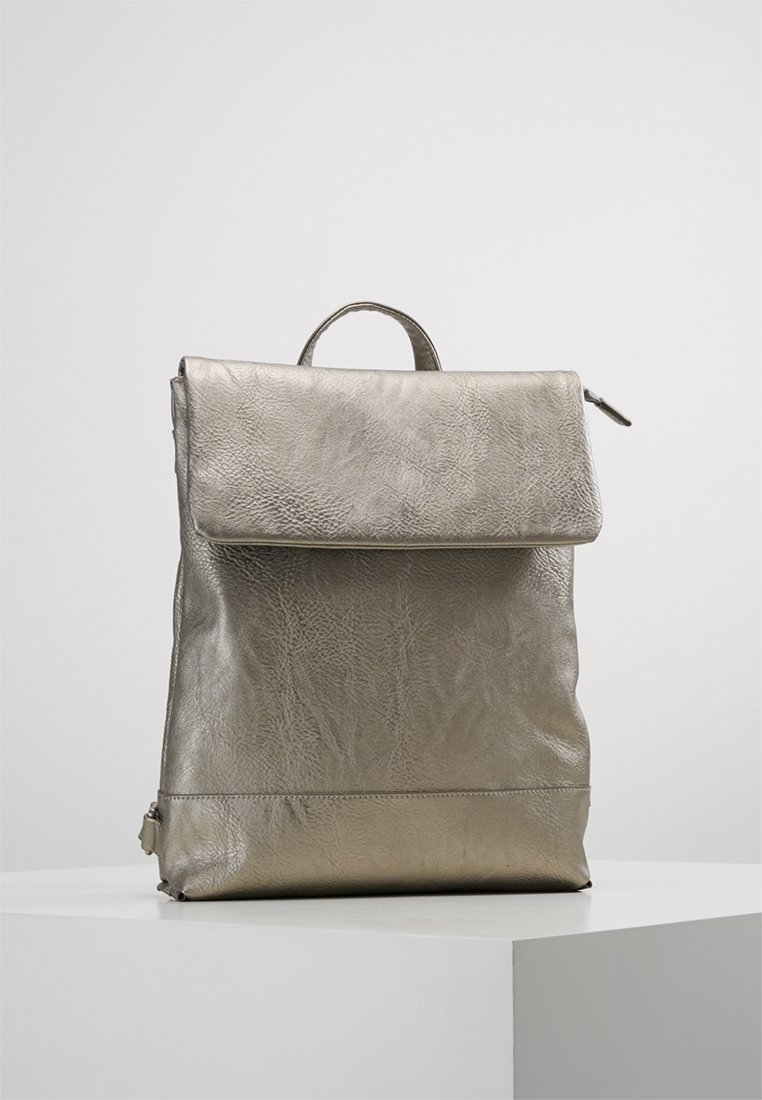 Metallinen hopeinen nahkarepulla, jossa on läppäkiinnitys ja yläkäsikäsi, seisoo suorana valkoisella jalustalla yksinkertaista taustaa vasten.