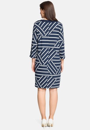 Robe bleu marine avec motif à rayures géométriques blanches, dotée d'un col rond et de manches trois-quarts, arrivant au-dessus du genou.