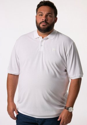 Polo shirt blanc avec une texture douce, doté d'une patte de boutonnage à trois boutons et d'un petit logo brodé sur la poitrine gauche. Associé à un jean sombre.