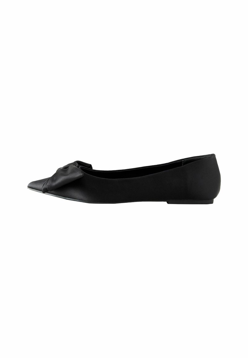 Chaussure plate noire à bout pointu avec un détail de nœud doux à l'avant et un petit talon plat sur fond blanc.
