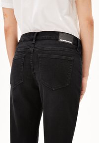 Svarta denimjeans med rak passform, två bakfickor med sned söm och en märke i läder vid midjan.