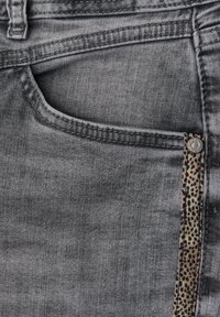 Jeans de mezclilla gris con un bolsillo lateral, un distintivo acento de estampado de leopardo en la cintura y detalles de costura visibles.