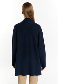 Cardigan lungo blu navy realizzato in materiale morbido, con colletto alto e vestibilità comoda, texture liscia e dettagli hardware minimi.