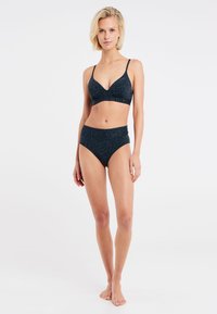 Sort bikini-sæt med et struktureret zebra mønster. Toppen har en dyb udskæring og justerbare stropper; de højhalsede bukser fuldender looket.