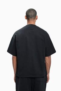 Sort kortærmet t-shirt lavet af bomuld, med en afslappet pasform og lige kant. Ingen synlige mønstre eller detaljer.