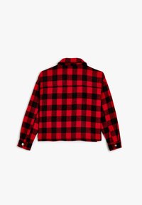 Rød og sort ternet flannel skjorte med krave, lange ærmer og knapmanchetter. Kropskort silhuet med struktureret stof.
