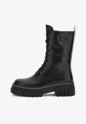 Stivali da combattimento neri in pelle con lacci, suola in gomma spessa, dettagli in cucitura bianca e una toppa con logo sul lato.