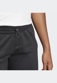 Pantalones deportivos negros con cinturilla elástica y cordón, que presentan una textura suave y un corte relajado.