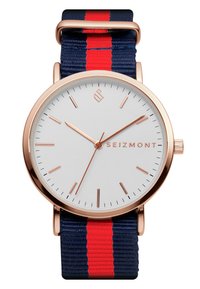 Rosa gull klokke med hvit urskive, med slanke timemarkører. Sammen med et tekstilarmbånd i marineblått med røde striper.