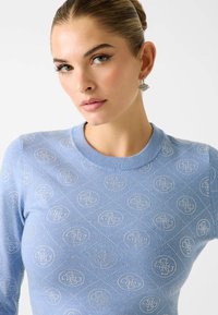 Maglione azzurro chiaro con scollo rotondo caratterizzato da un motivo a rilievo con loghi argentati e forme a diamante. Tessuto a maglia liscia.