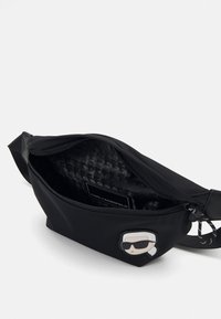 Črn nylon bum bag z zadrgo, z vzorčasto notranjostjo in risano insignijo spredaj.