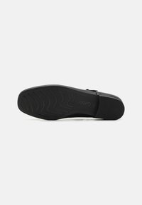 Schwarze Schuhsohle mit strukturiertem Gummibelag, der Zickzackmuster für besseren Halt aufweist, sowie geprägt auf der Seite mit Branding.
