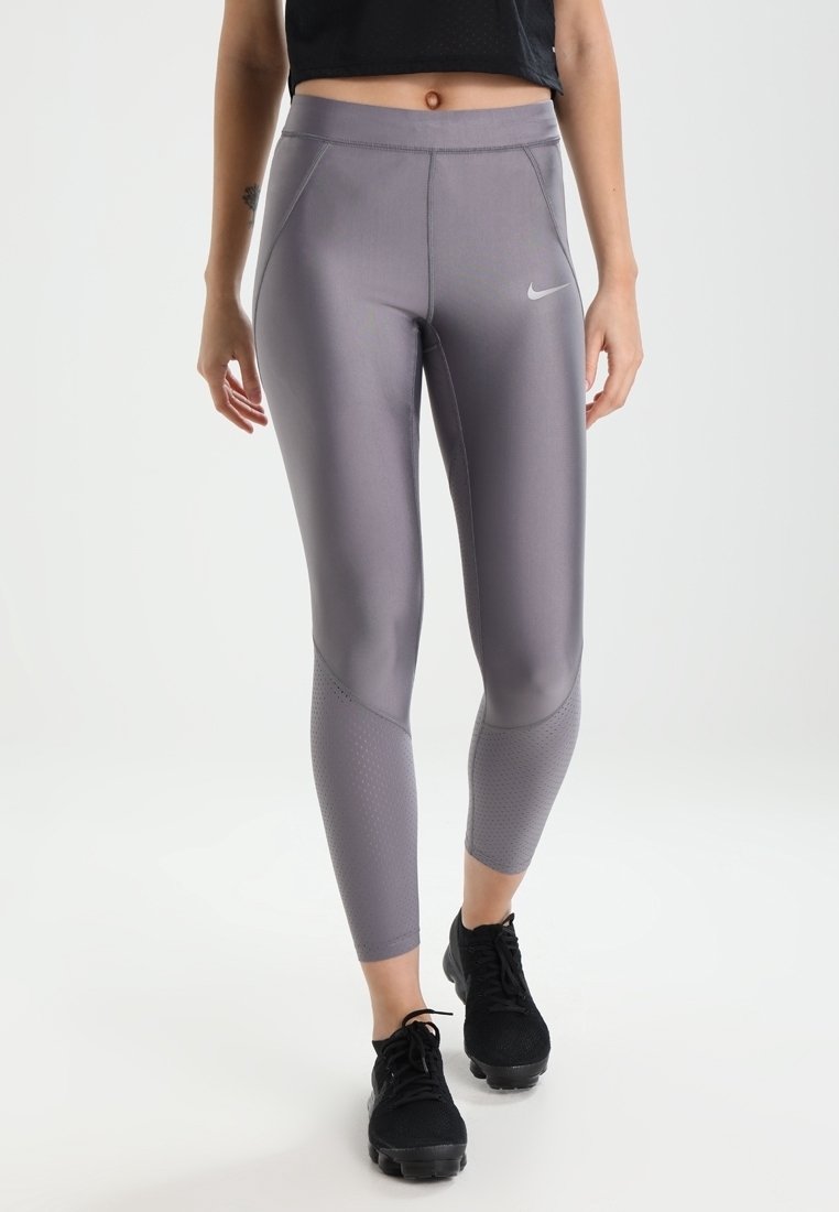 Leggings sportivi grigi realizzati in un tessuto morbido e elasticizzato, con pannelli in rete, vita alta e un piccolo logo bianco sul davanti.