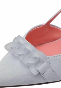 Chausson plat en suède gris clair avec un bout pointu, doté d'un détail en chaîne translucide et d'un intérieur rose. Sangle ajustable incluse.