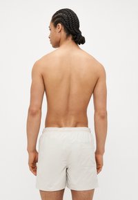 Herre beige badeshorts med elastisk midjebånd og baklomme. Glatt tekstur og lett materiale, egnet for sommerbruk.