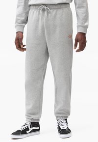 Gray sweatpants made of cotton blend, featuring an elastic waistband with drawstring, ribbed cuffs, and a small logo detail on the thigh.