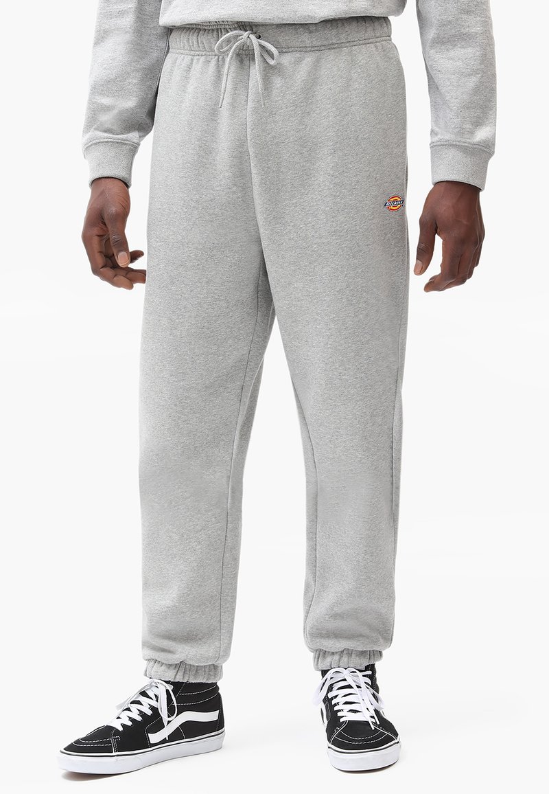 Gray sweatpants made of cotton blend, featuring an elastic waistband with drawstring, ribbed cuffs, and a small logo detail on the thigh.