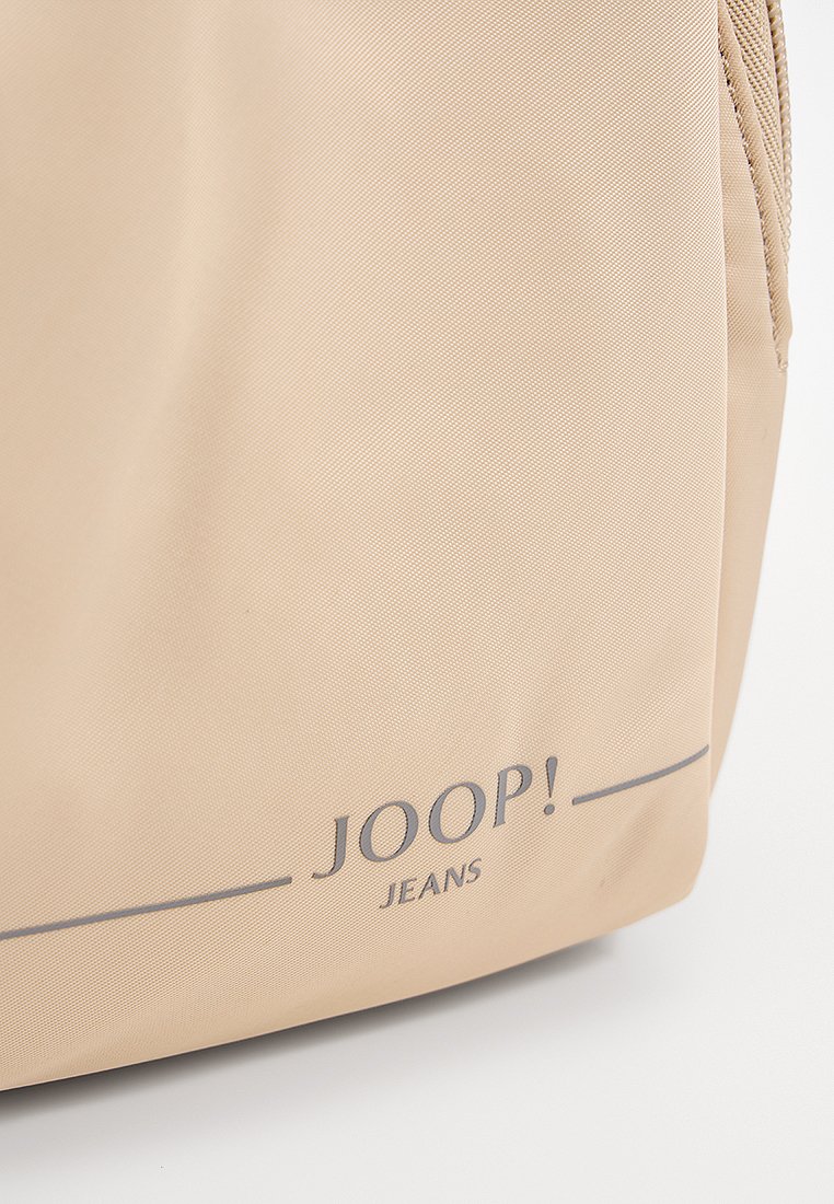 Beige Nylon Tasche mit glatter Textur, featuring ein dunkelgraues Logo "JOOP! JEANS" und einem subtilen horizontalen Linienakzent. Mit Reißverschluss.