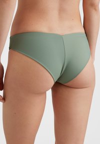 Grön bikiniunderdel gjord av mjukt, elastiskt material. Har en låg midja och minimal täckning bak med en subtil, glänsande metallaccent.