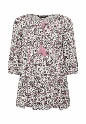 Blusa blanca con estampado floral en rosa y negro, mangas 3/4, lazos de borlas en el escote redondo y detalles de costuras verticales en rosa.