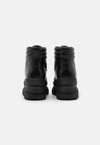 Bottes courtes en cuir noir avec col rembourré, semelle en caoutchouc et accents texturés. Dotées d'une languette à l'arrière pour un enfilage facile.