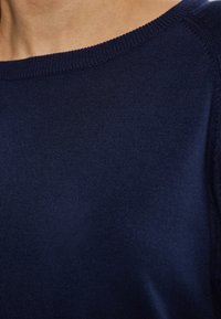 Marineblauer Strickpullover mit geripptem Kragen und glattem Textilmaterial, Nahaufnahme des Stoffes.