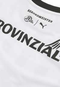 Bela športna majica z črnimi napisi. Značilnosti vključujejo okrogel ovratnik, teksturirano blago in logotipe "REKORDMEISTER" ter "PUMA."