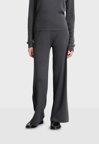 Grijze ribgebreide trui en brede broek, met lange mouwen, een getailleerde pasvorm en een zachte textuur, gecombineerd met zwarte schoenen.